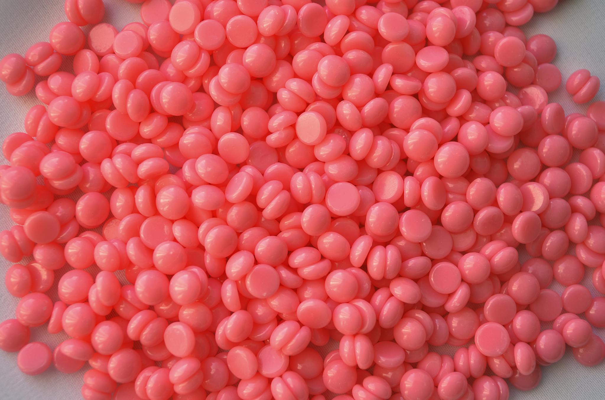 Close-up of pink wax beads used in cosmetic depilation and hair removal treatments.